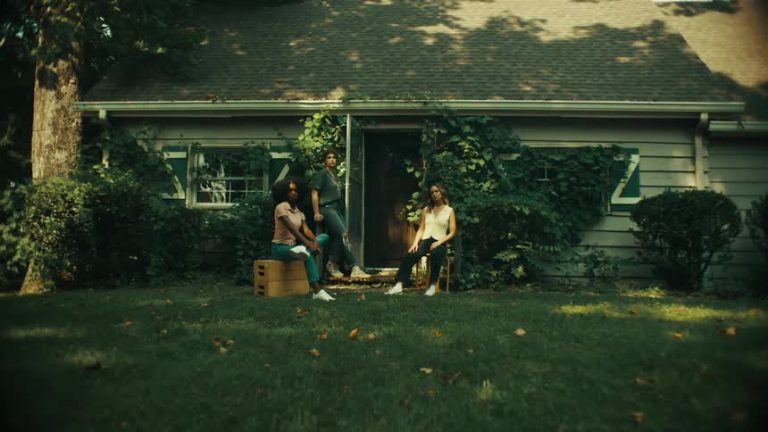 Three diverse female friends pose in front of their home