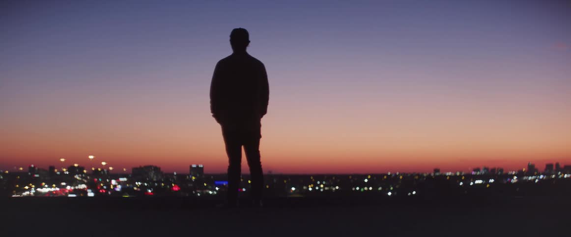 Man walking in the top of a building during sunset with a big city at the background