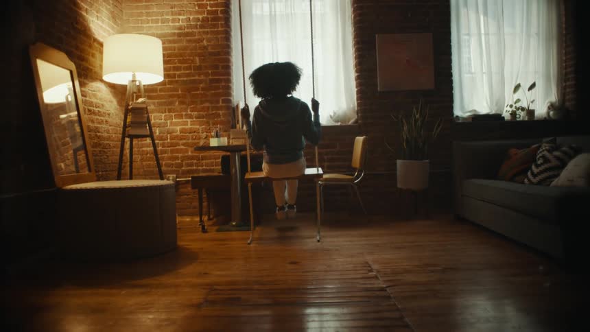 A woman sits on a swing inside her living room