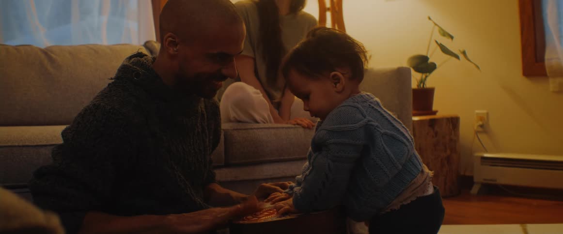 Mother watches father play with toddler as they drum on toy together