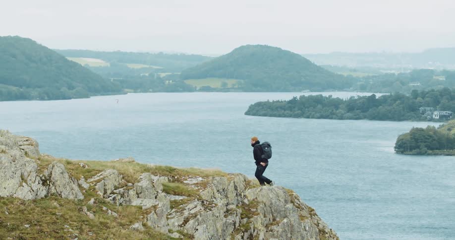 A man climbs up the side of a large mountain beside a river