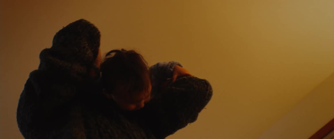 Father holding and lifting his son in the air while both laugh and have fun inside the house