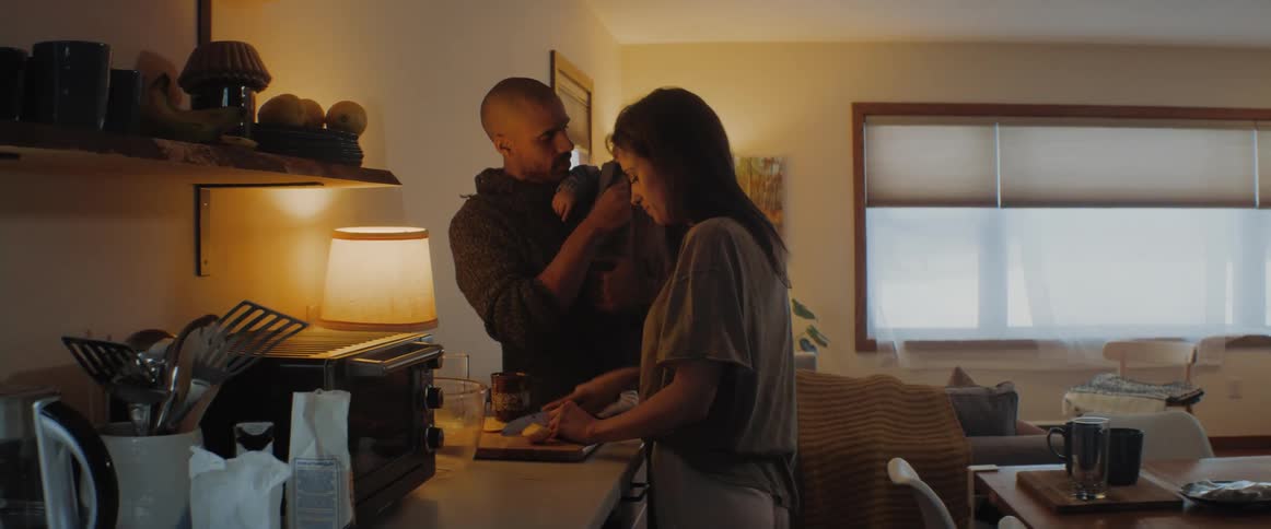 A mother is cutting food as a man and baby watch