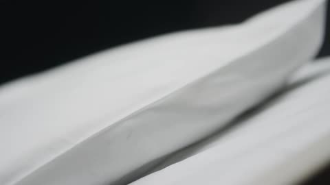 White linens sit on a hospital bed in a dark room