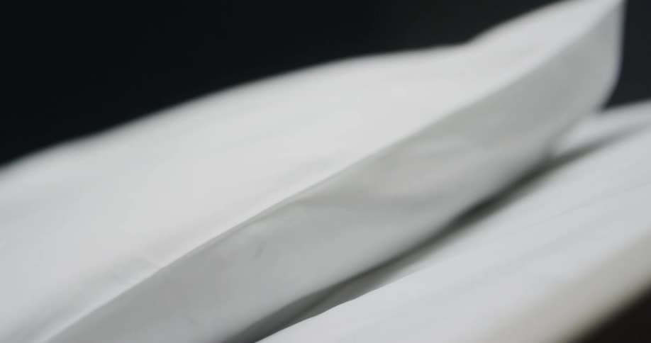 White linens sit on a hospital bed in a dark room