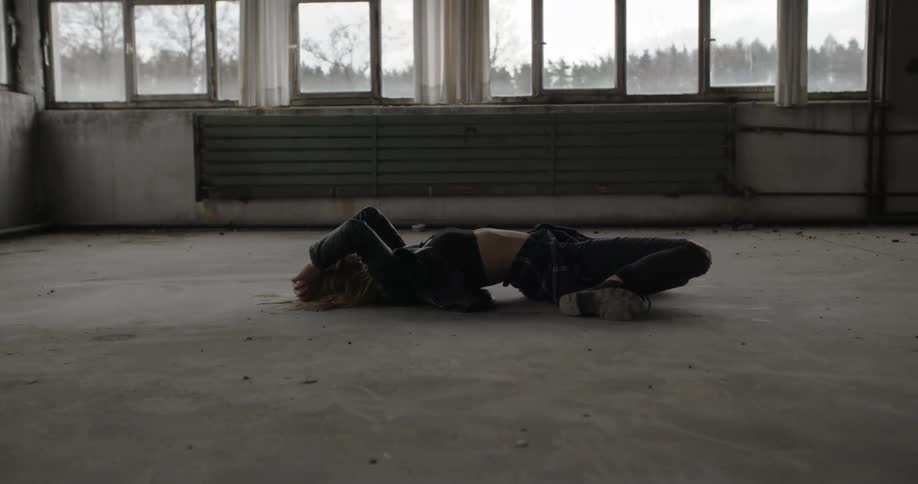 A woman kneeling on the floor falls over backwards