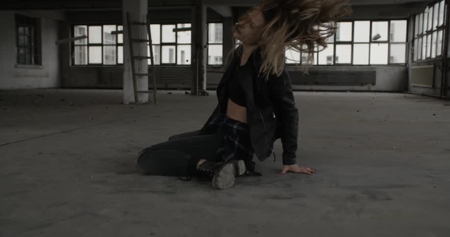Woman twirling her head on floor of abandoned building