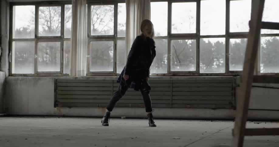 A woman dances by herself in a warehouse