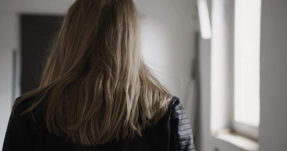 A blonde woman walks down a brightly lit hallway