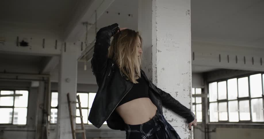 A woman practicing dance moves in an empty warehouse