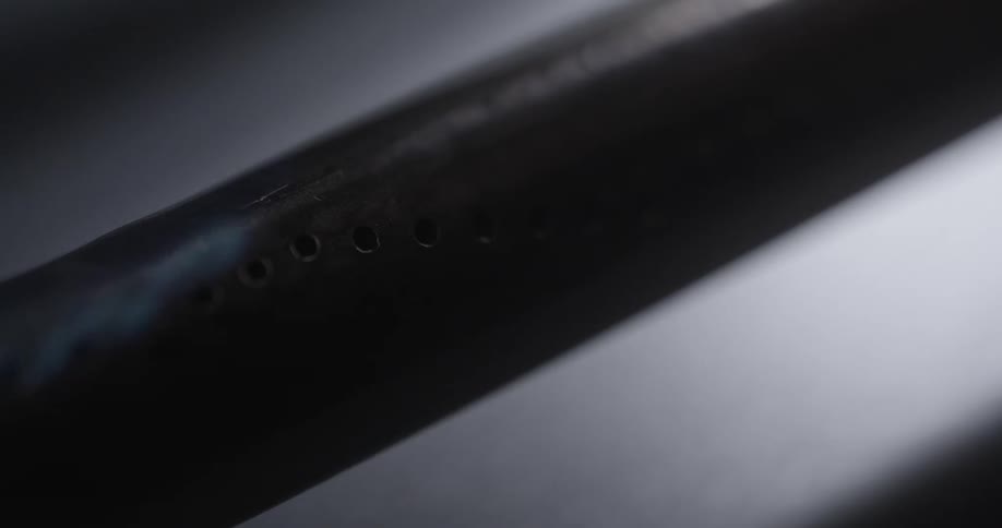 The holes in a burner fill with blue gas flames