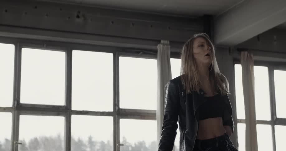 A woman in black dances in front of some windows