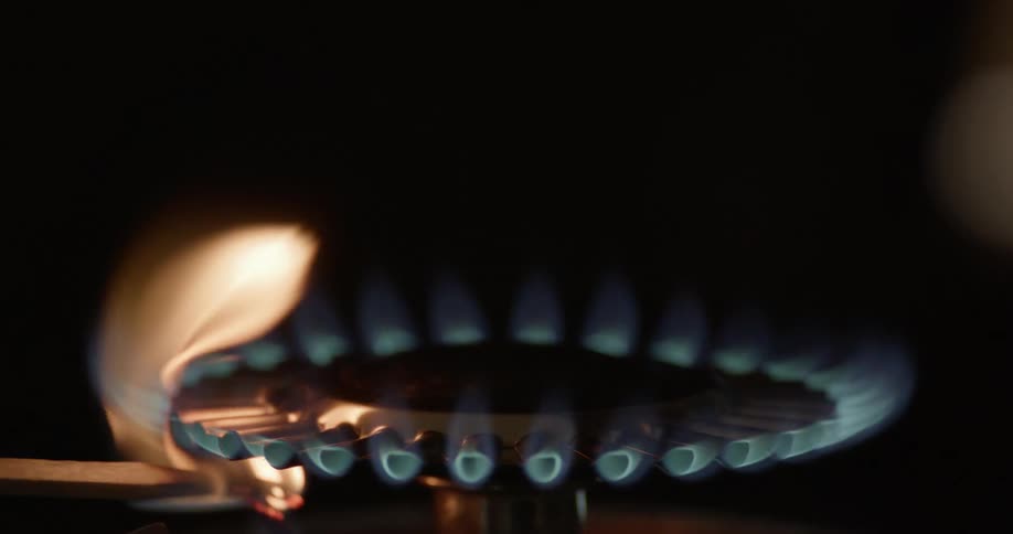 A match ignites the flames on a stove burner