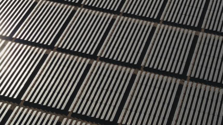 The sun is shining brightly on solar panels on a solar farm