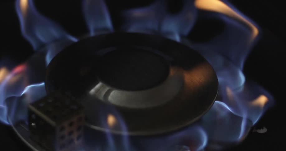 The blue flames from a gas stove burner are wavering