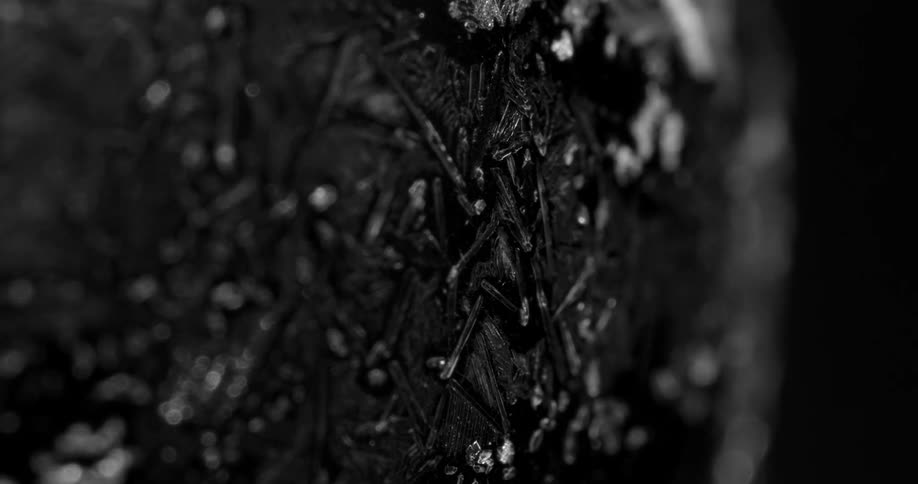 A closeup of a dark surface reveals small crystalline structures embedded within it