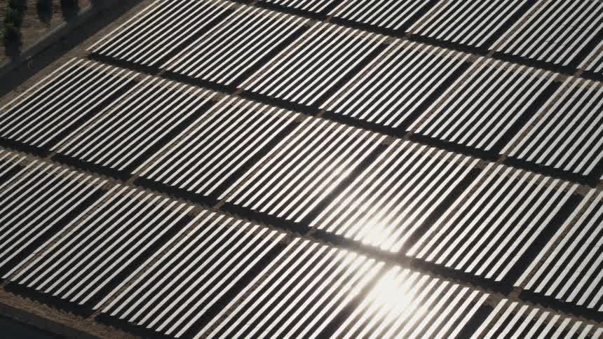 The sun is shining brightly on solar panels on a solar farm