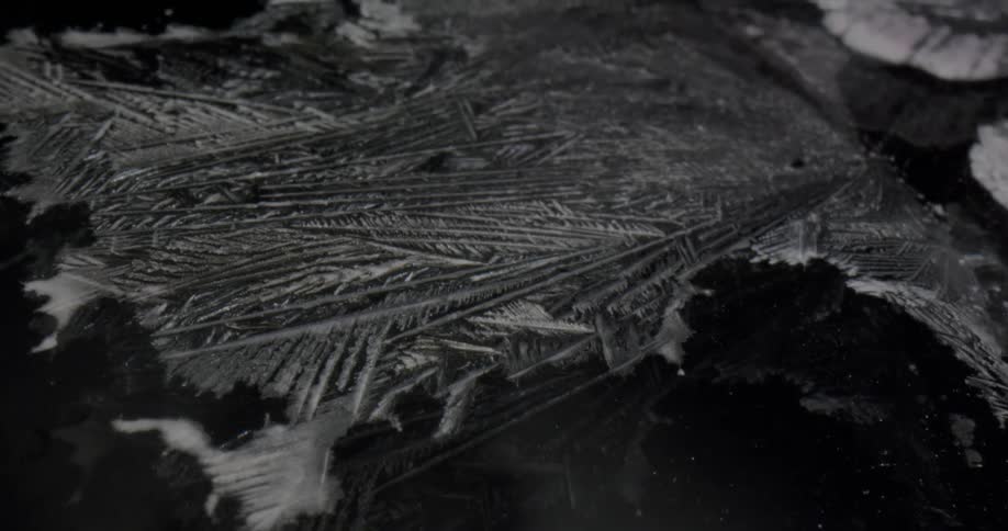 Textured surface of ice crystals show white against dark of water