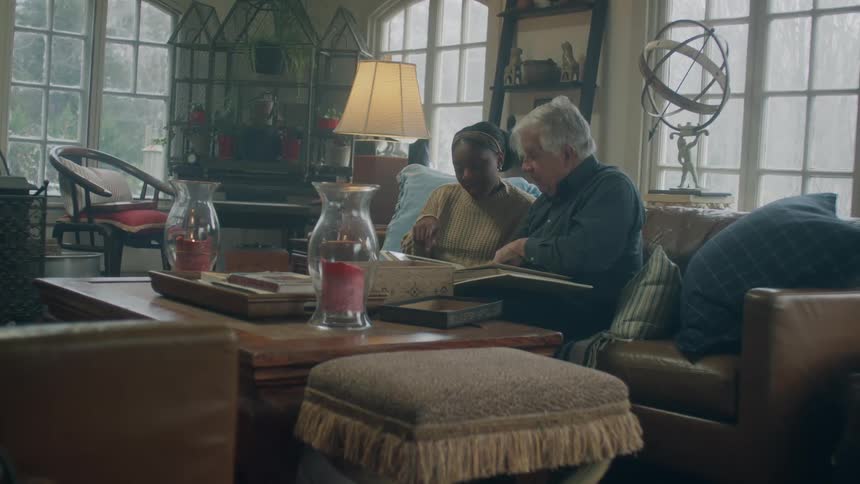 Man and woman sit in living room going through photo albums
