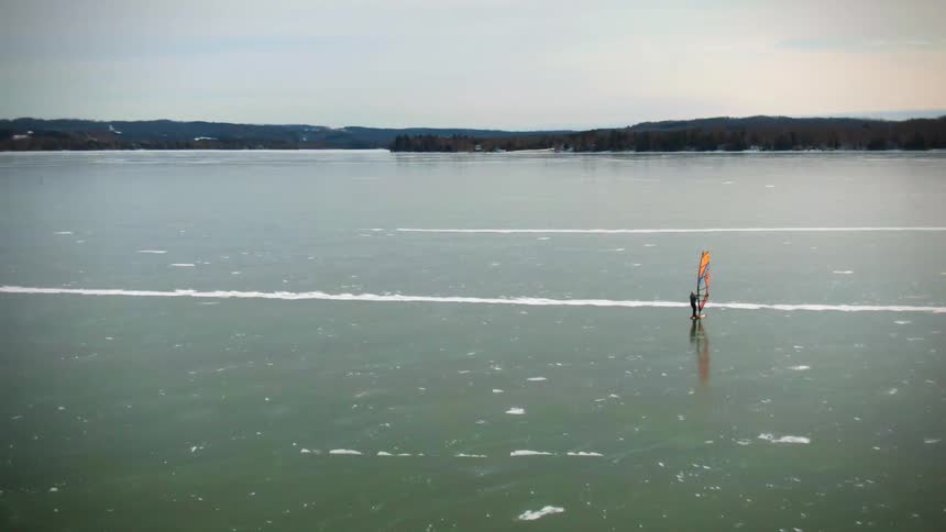 Windsurfer surfs on the lake as trees sit in the distance