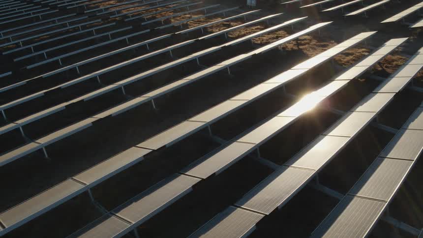 The sun is shining brightly on solar panels on a solar farm