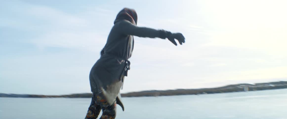 A woman performing ice skating in what seems to be a frozen lake