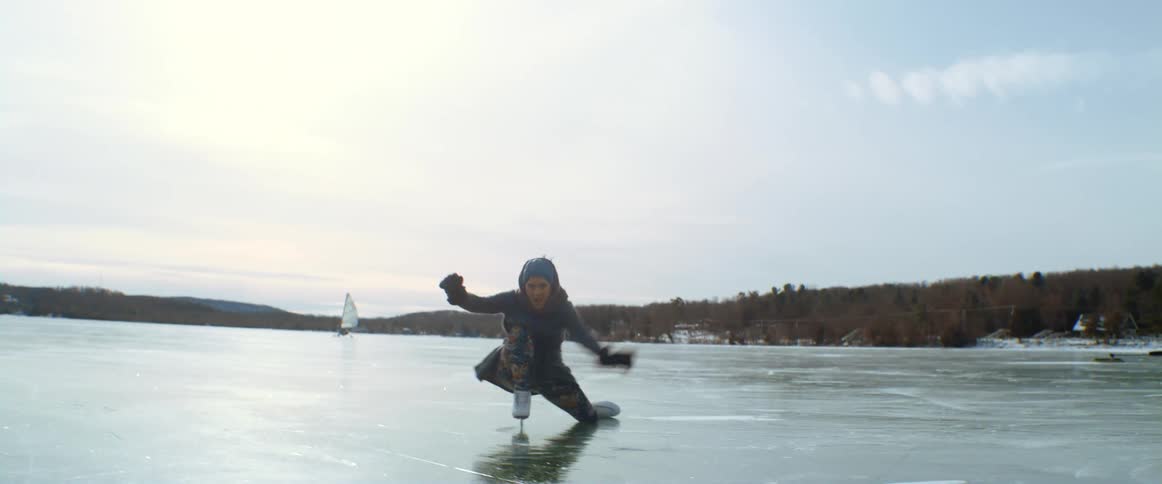 A woman skates on a frozen lake and falls down