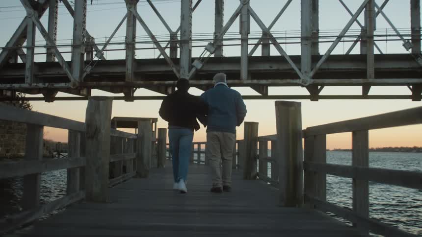 A man and woman walk arm in arm on the pier