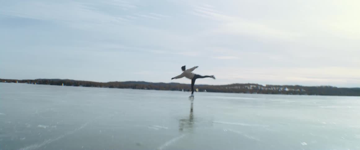 Female ice skating on a frozen lake on a beautiful day