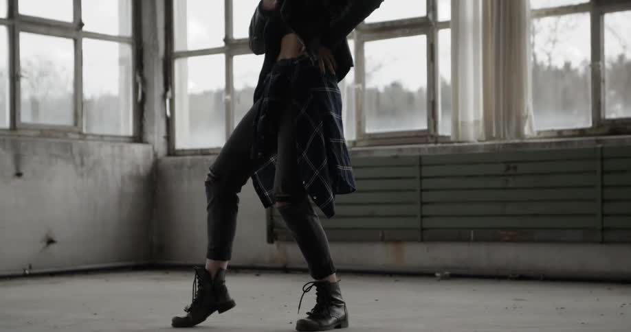 A young, blonde woman dancing in a vacant room