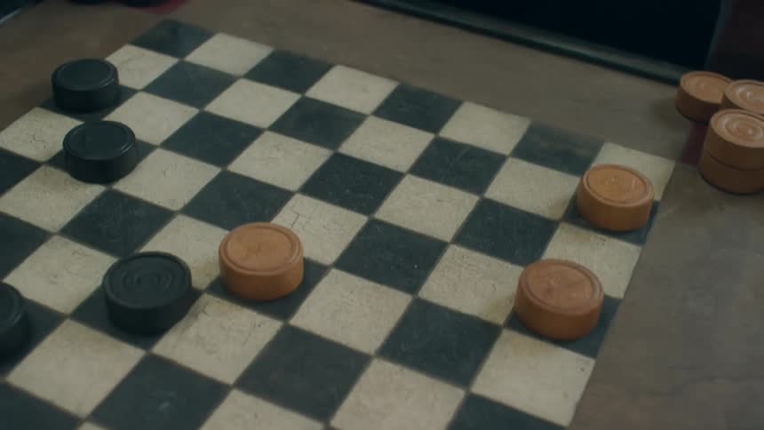 Closeup of an elderly man and younger woman playing checkers