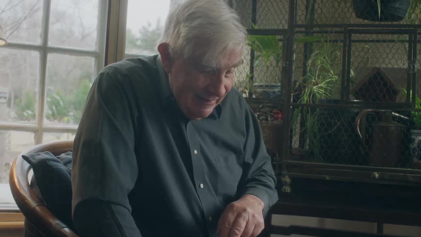 Old white man and black woman sitting next to the window playing checkers