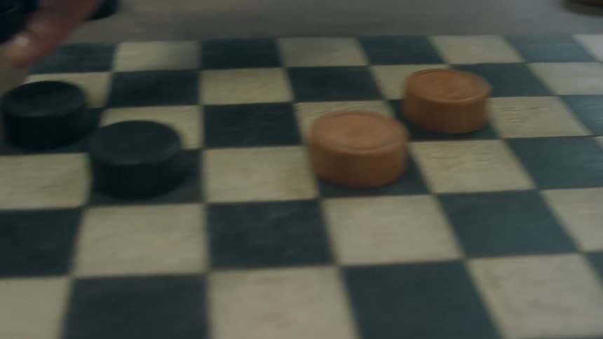 Closeup of two people playing checkers with last two pieces