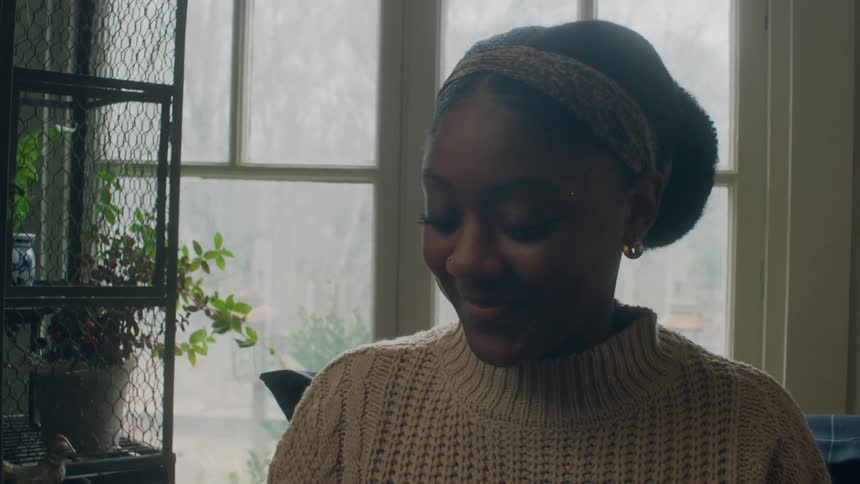 A woman smiling and talking at home in front of window