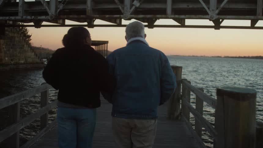A man and woman walk on the pier together