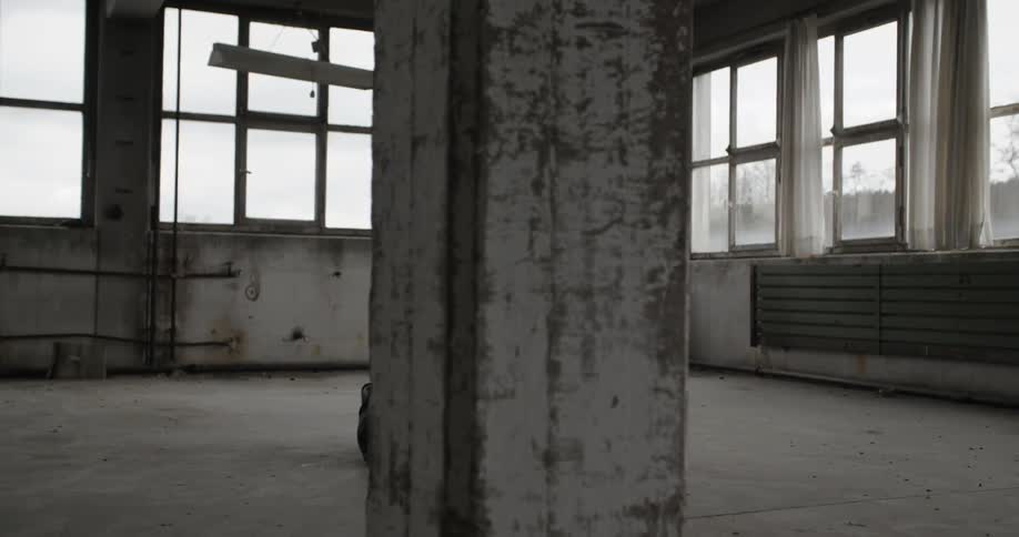 A woman is dancing in the upper story of an empty warehouse building