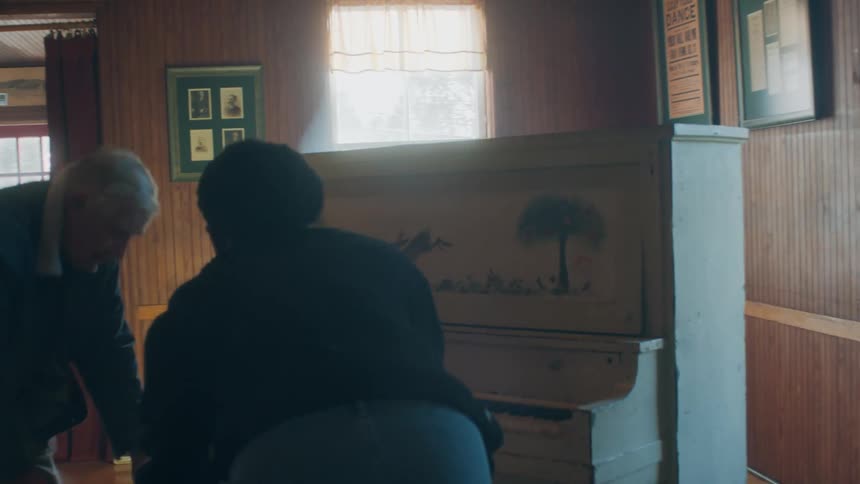 A man and woman sit by the piano