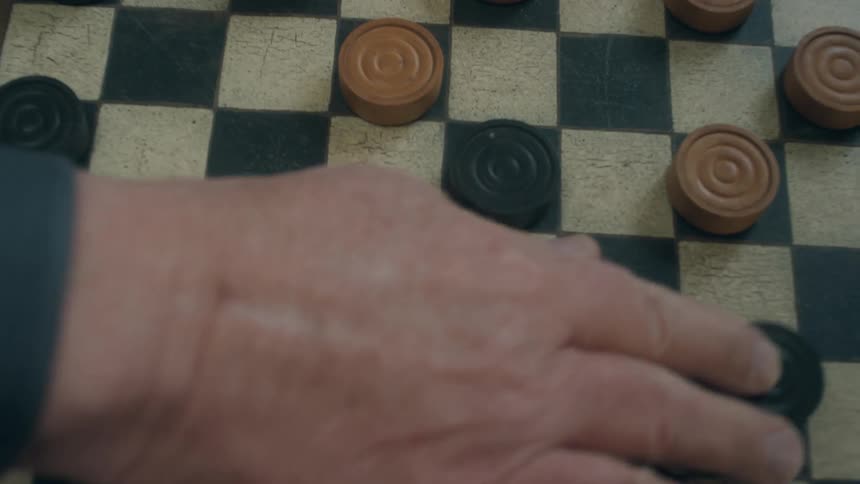Two people are moving checkers pieces around