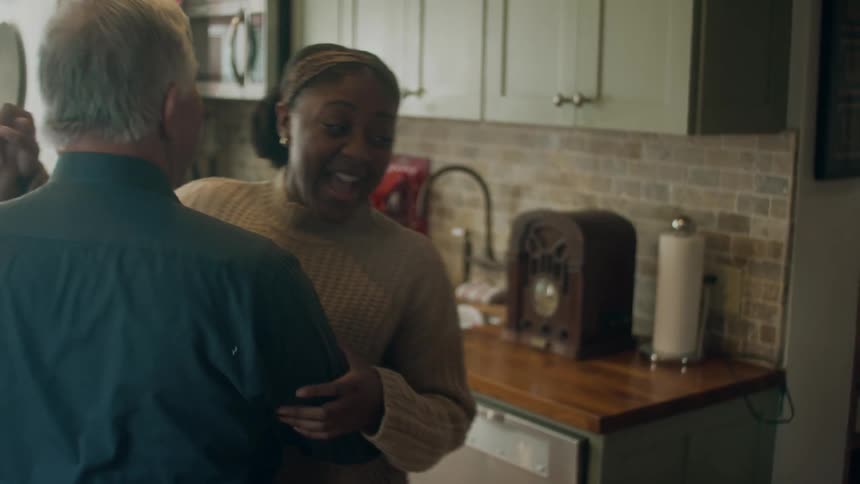 Older man and woman dance in kitchen near where old style radio sits on the counter