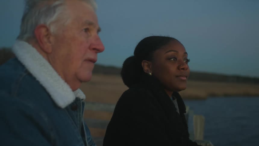 A man and woman talk by the shore