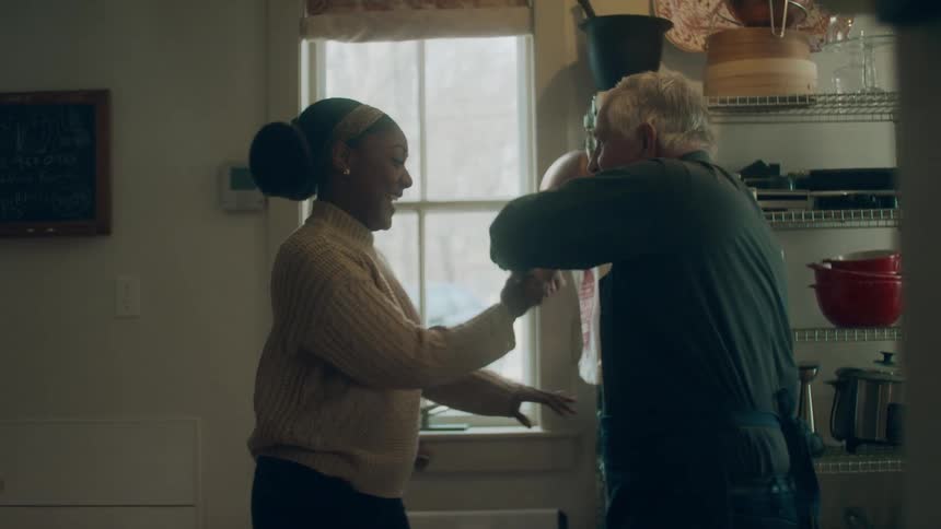 Man and woman dance in kitchen near shelves of kitchen appliances
