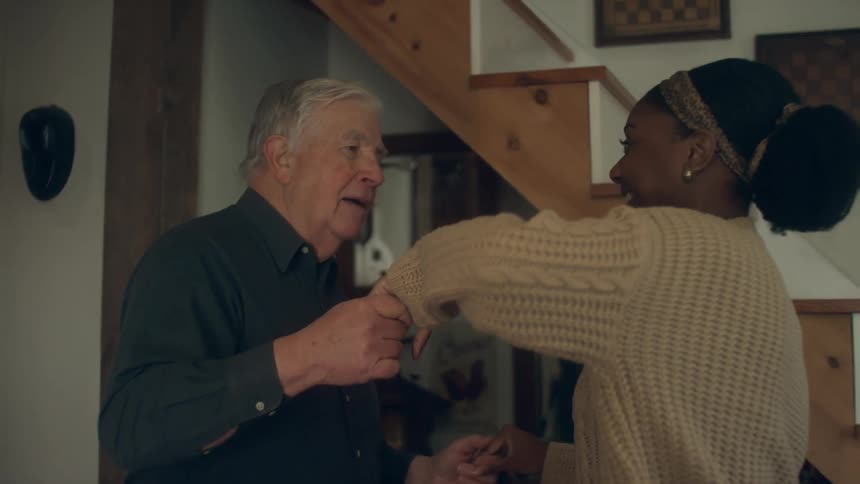 A young woman dances with an elderly man in a house