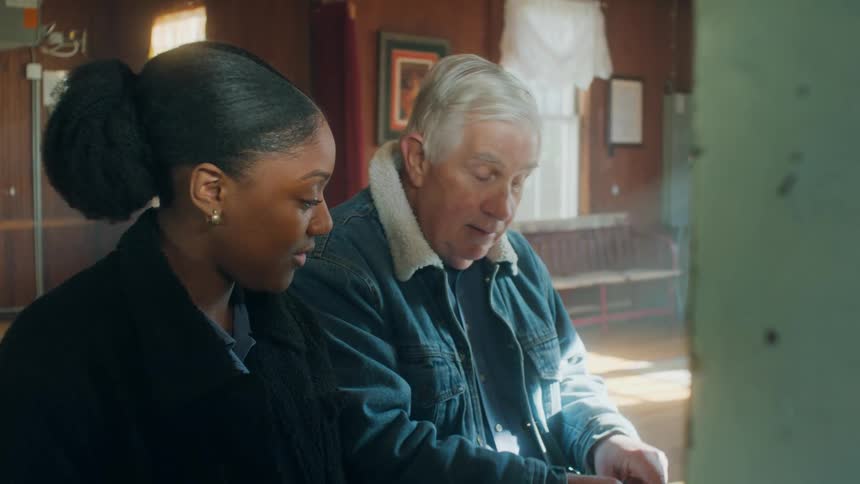 A man is showing a woman how to play the piano
