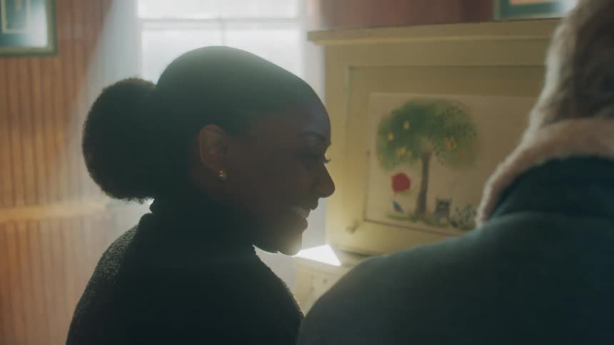 A man and woman laugh as they sit and play the piano