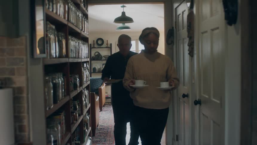 A man and woman walk down the hall with food and drinks