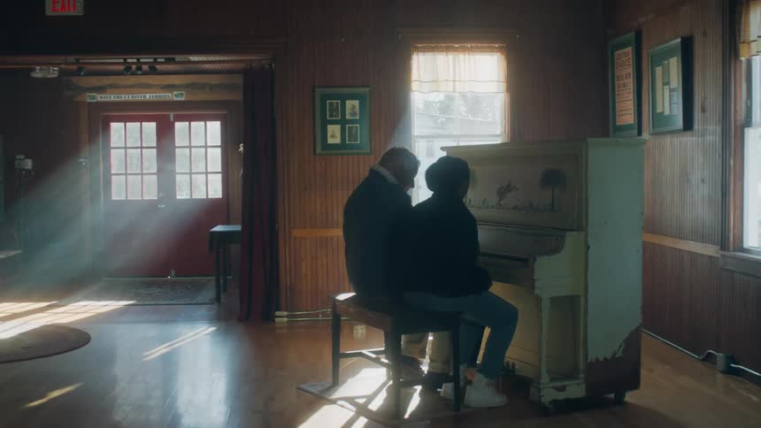 Elderly man with denim jacket and woman play piano in big room