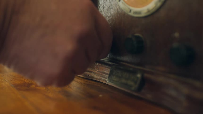 A man turns on the knob to a vintage radio