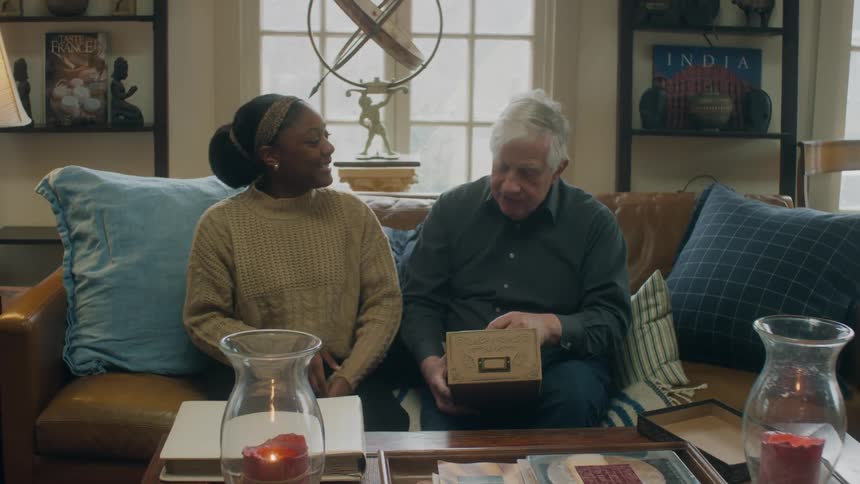 A man and woman talk on the couch
