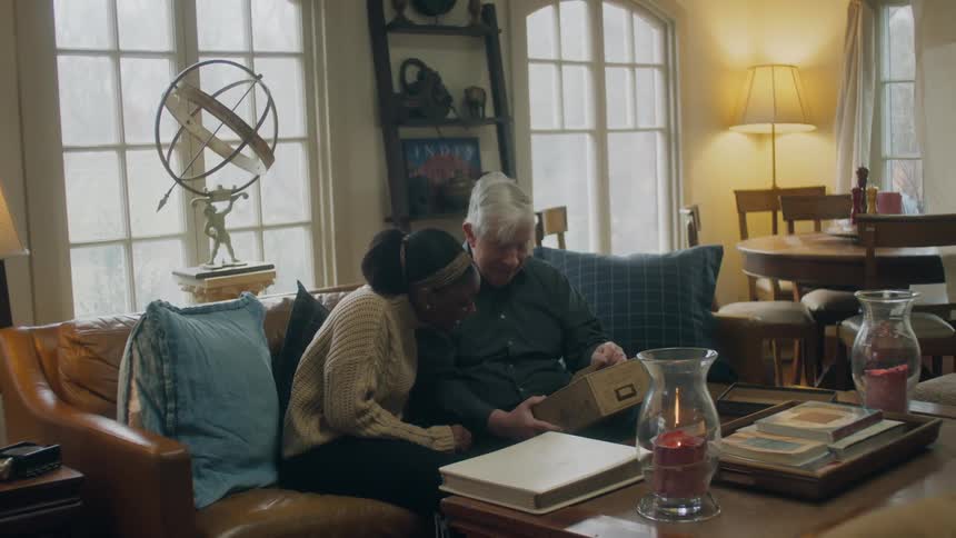 A man and woman look at photos on the couch