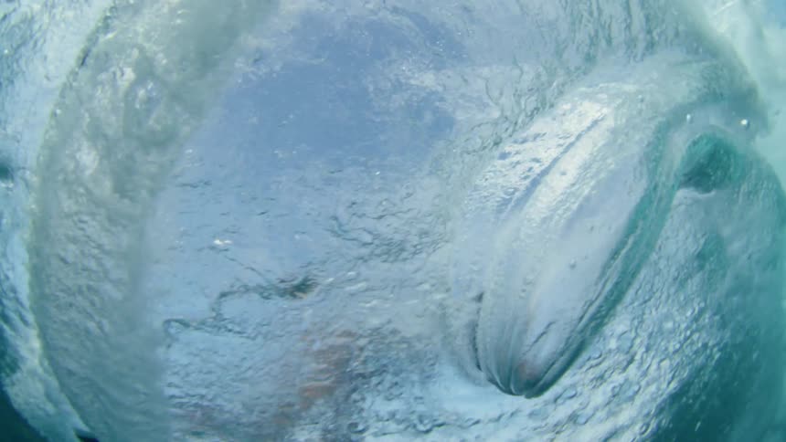 dynamic shot of surfers hand dragging across the surface of wave